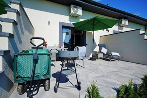 A patio area with a green cart, outdoor furniture, and air conditioning units on the building. - Holiday homes with terraces, Mielenko (Mielenko)