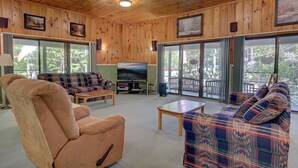 A cozy living room with wooden walls, a large TV, and a sofa. - Cozy Condo at The Seasons Resort – Perfect for Skiing, Hiking & Family Fun 🎿❄️🏂🌲🗻 (Bartlett)