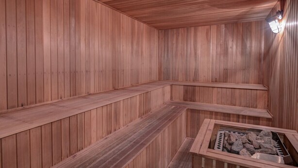 A sauna with wooden walls and benches, a stone basin, and a light fixture. - Cozy Condo at The Seasons Resort – Perfect for Skiing, Hiking & Family Fun 🎿❄️🏂🌲🗻 (Bartlett)