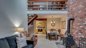 A cozy living room with a sofa, a dining table, and a kitchen in the background. - Cozy Condo at The Seasons Resort – Perfect for Skiing, Hiking & Family Fun 🎿❄️🏂🌲🗻 (Bartlett)