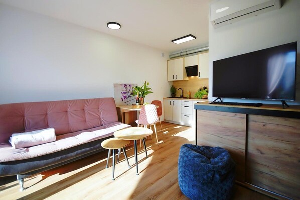 A modern living room with a sofa, a coffee table, a TV, and a kitchen area in the background. - Comfortable and spacious holiday home, Mielenko (Mielenko)