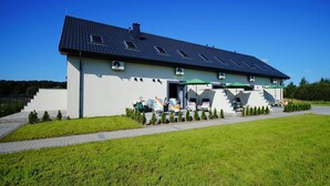 A two-story building with a flat roof, a covered outdoor seating area with umbrellas, and a well-maintained lawn.