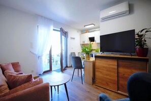 Ein modernes Wohnzimmer mit einer Couch, einem kleinen runden Tisch und einem Fernseher auf einem Holzschrank.