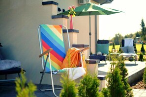 Ein Poolbereich mit einem bunten Stuhl, einem grünen Sonnenschirm und einer Blumenvase.