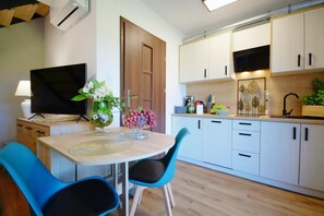A modern kitchen with white cabinets, a black microwave, and a dining area with a table and chairs.