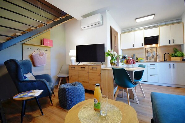 A modern living room with a sofa, ottoman, and a TV on a wooden cabinet.