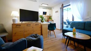 En moderne stue med TV, sofa og spiseplads.