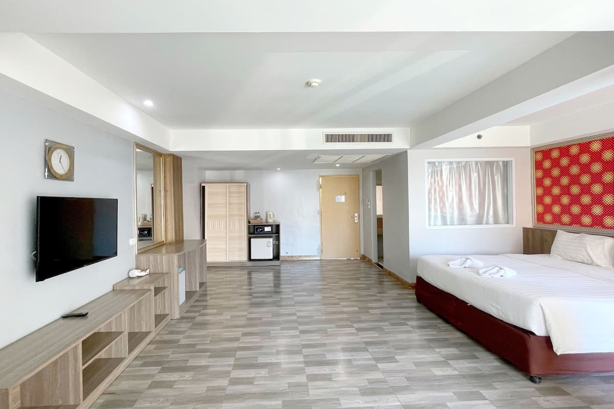 Ein Hotelzimmer mit Bett, Fernseher, Schreibtisch und Kleiderschrank.