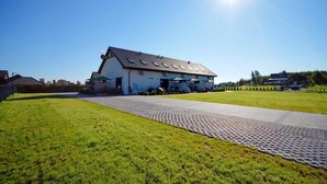 En stor byggnad med ett sluttande tak och en stenlagd gångväg som leder till entrén.