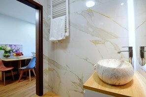 Ein Badezimmer mit Marmorwand, einem Waschbecken aus Marmor und einem Handtuch an einem Halter.