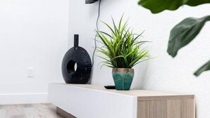 Un'accoglienza moderna con una consolle bianca, una pianta in vaso e un elemento decorativo nero a parete.