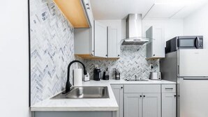 Una cucina moderna con mobili bianchi, un lavello in acciaio inossidabile, un forno a microonde e un forno integrato.