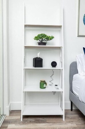A white shelving unit with a potted plant, a tissue box, a clock, and a jar. - Stylish & Modern Studio in Phoenix ~ QueenBed (Phoenix)