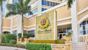 A hotel entrance with a prominent crest, palm trees, and a sign for the hotel restaurant. - Marco Beach Ocean Resort Unit 712 (Marco Island)