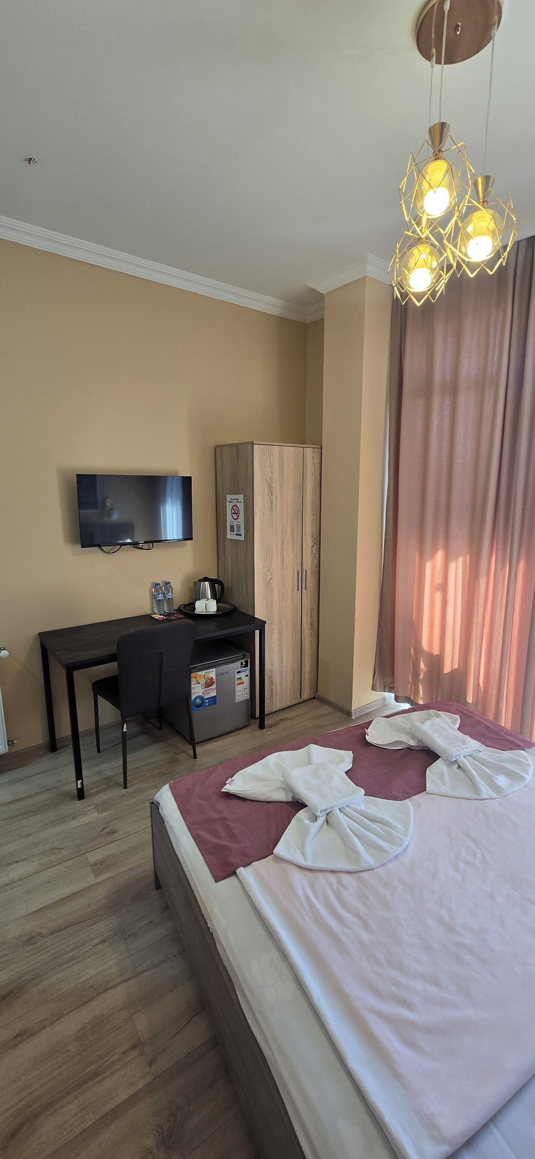 A hotel room with a bed, a desk, a television, and a wardrobe.