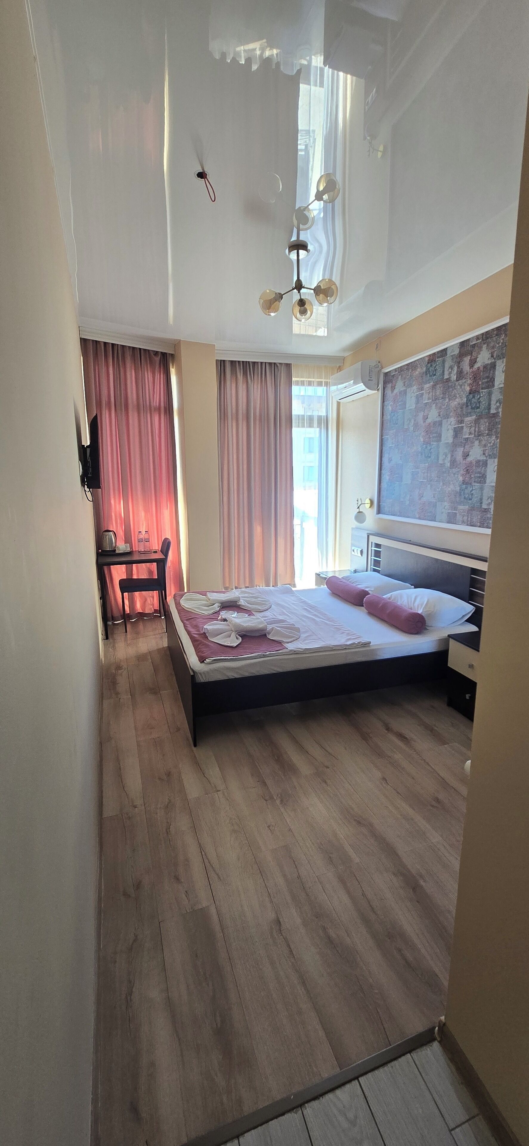 A bedroom with a bed, bedside table, and a desk with a chair.
