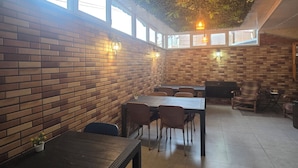 A restaurant with brick walls, wooden tables, and hanging plants. - Mahali Hotel (Batumi)