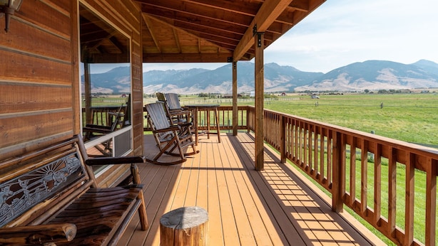 Eine Holzterrasse mit Bergblick, einem Schaukelstuhl und einer Bank.