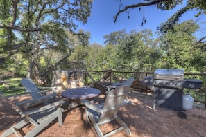 An outdoor patio with Adirondack chairs, a round table, and a grill. - 406 Lodge-a: Hot-tub & 2 Blks to Main St (Fredericksburg)