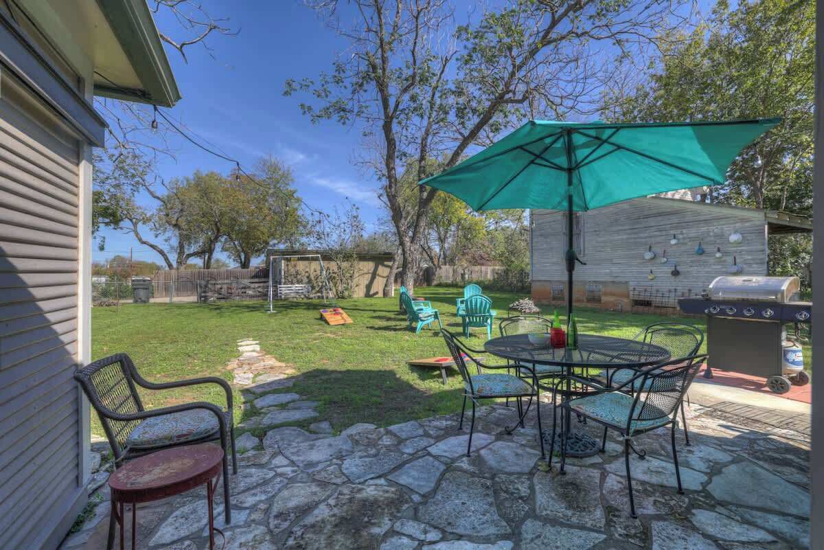 A patio with stone flooring, outdoor furniture, a grill, and a covered area with chairs.