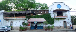 Un edificio con techo de paja, toldo azul y un letrero que indica que es un albergue.