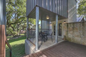 An outdoor patio area with a covered seating area, stone wall, and a view of the surrounding trees. - Schubert Place (Fredericksburg)