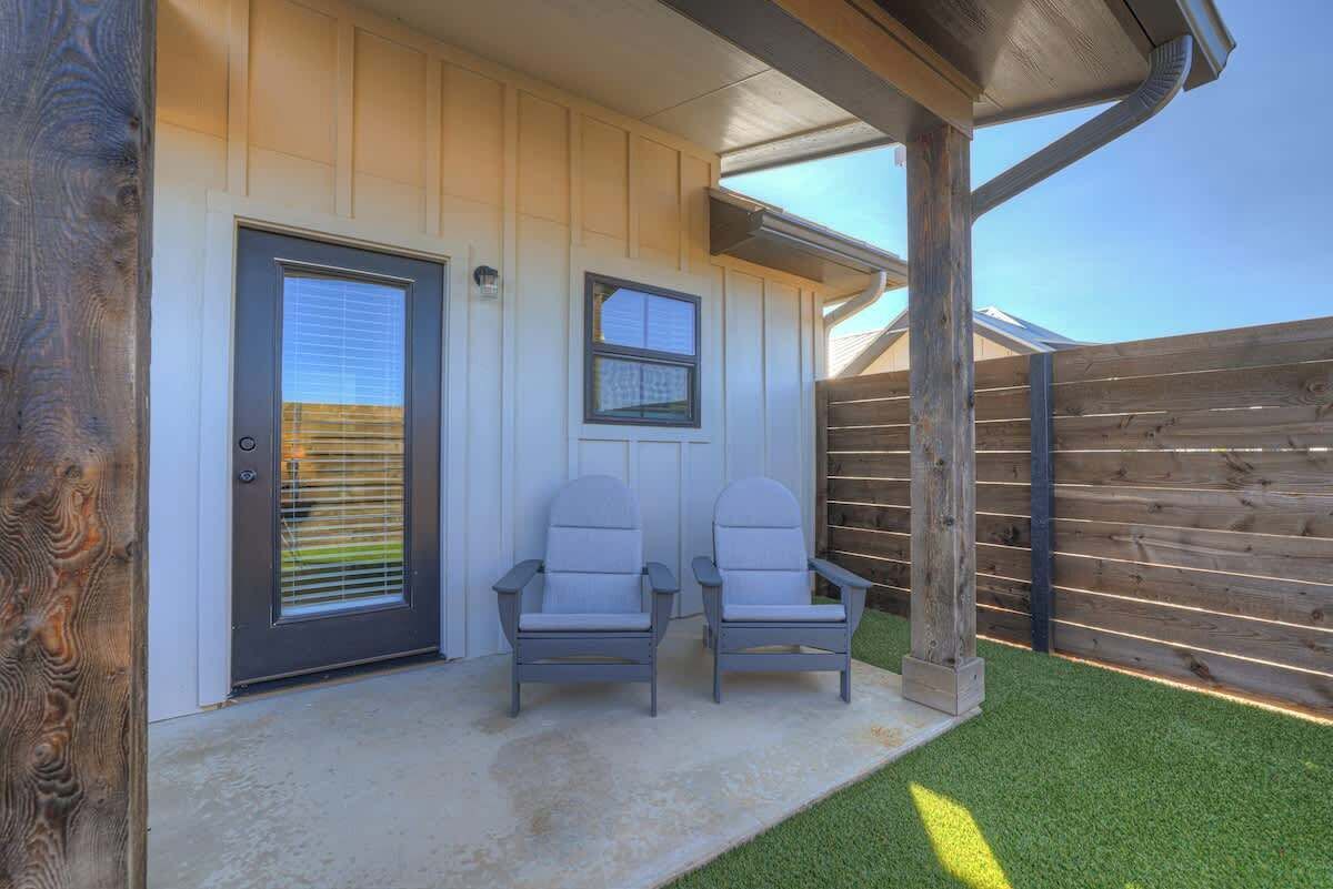 A house with a covered porch, two chairs, and a wooden fence.