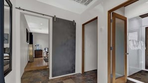 A modern interior with a sliding door, a wooden door, and a glass door leading to a bathroom. - Guest Quarters - 2 Blocks to Main Street! (Fredericksburg)