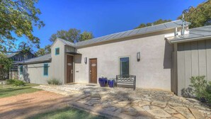 A modern house with a stone patio, a wooden door, and a metal roof. - Guest Quarters - 2 Blocks to Main Street! (Fredericksburg)
