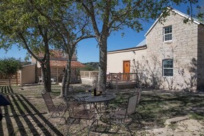 Een stenen gebouw met een deur, een overdekte patio en een ronde tafel met stoelen.