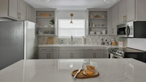 Una cocina moderna con armarios blancos, electrodomésticos de acero inoxidable e iluminación colgante.