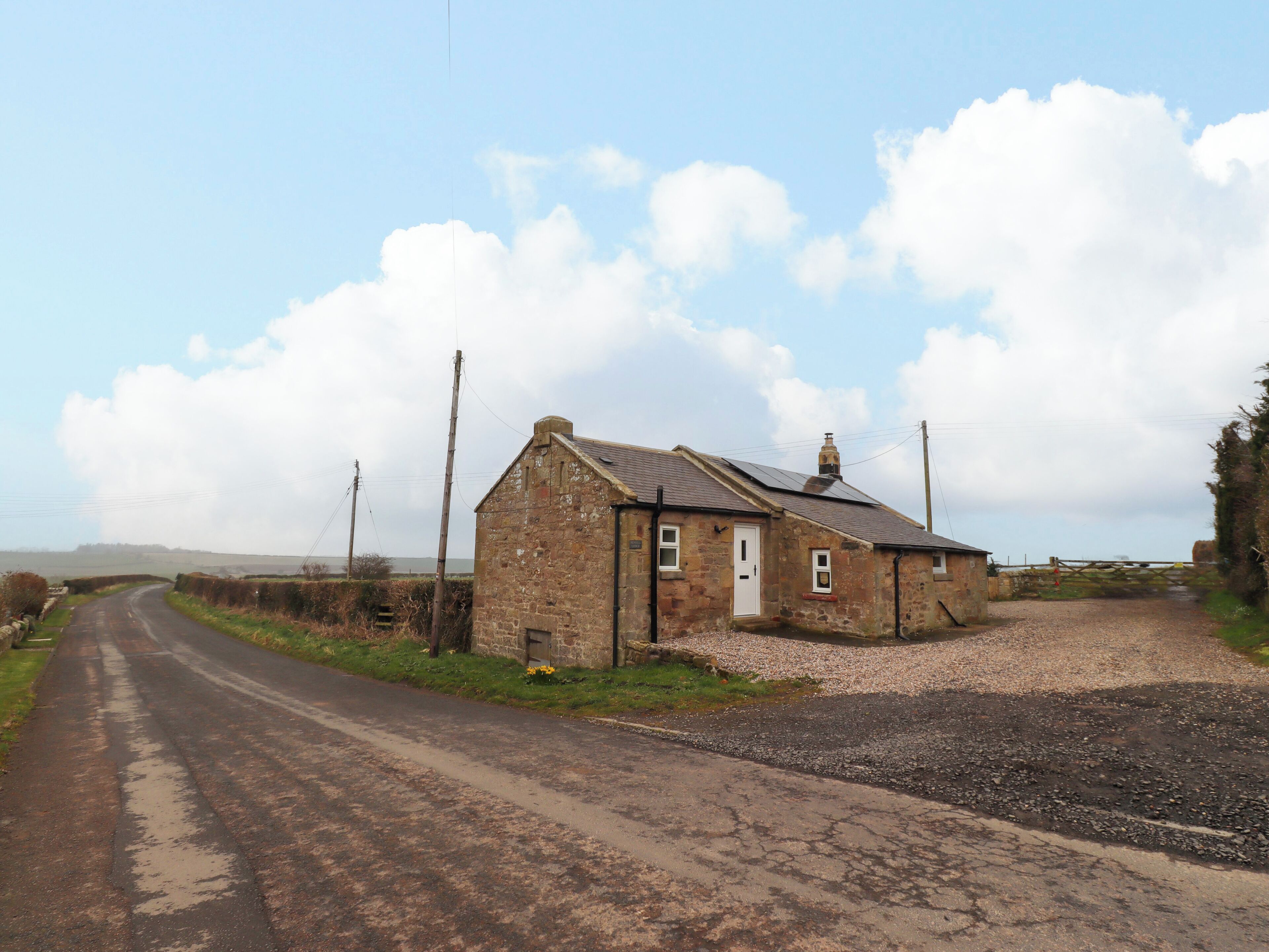 A rural road leading to a small stone house with a white door and a single window.