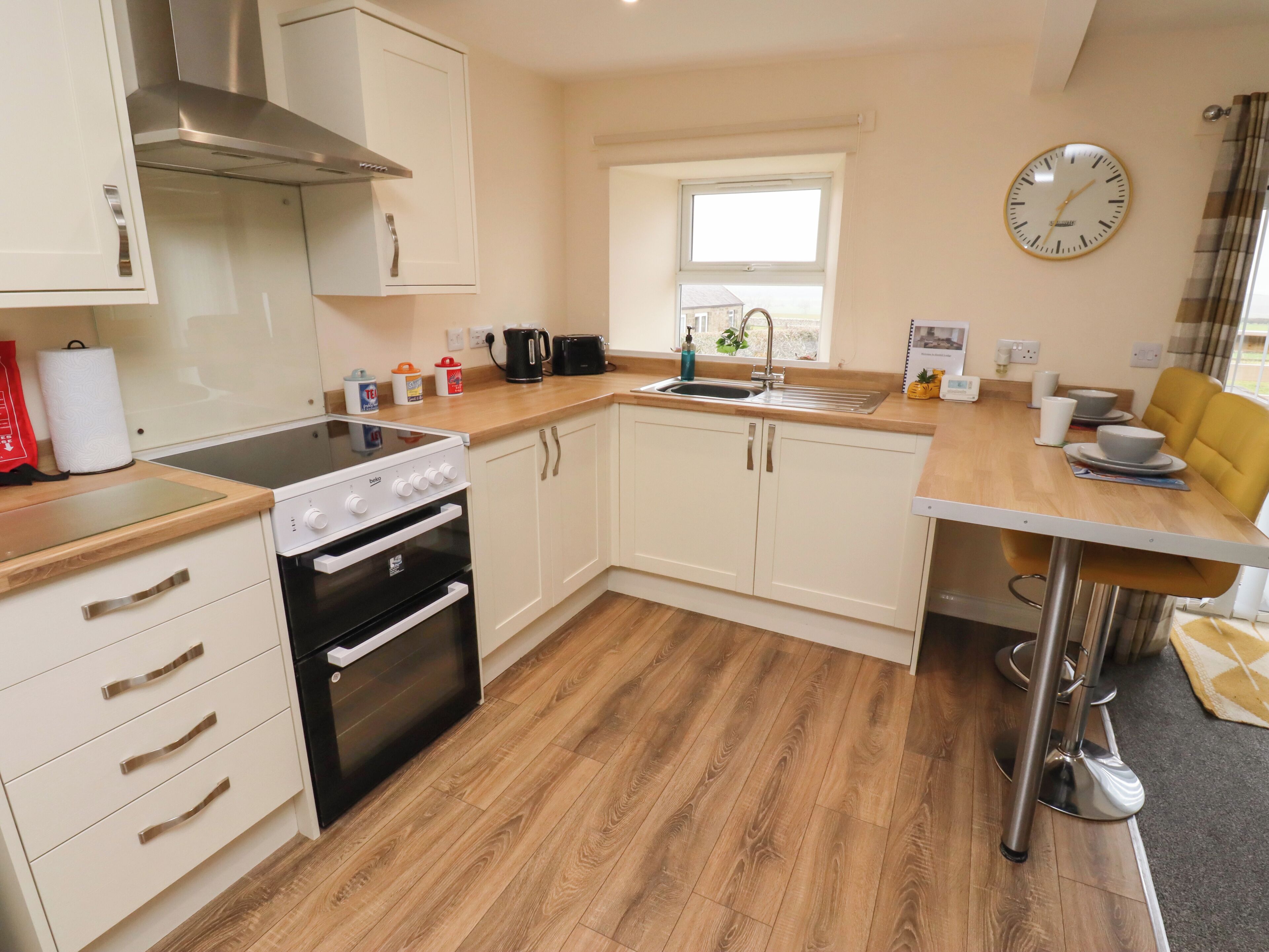 A compact kitchen with white cabinets, a built-in oven, a stove, and a window above the sink.