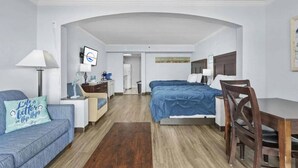 Ett hotellrum med en säng, ett skrivbord, en stol, en soffa och en tv.