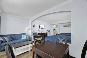 Habitación compacta con sofá, mesa de comedor, televisor y cama.