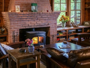 Una sala de estar acogedora con chimenea de ladrillo, muebles de cuero y una estantería.