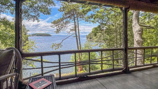 A covered deck with a view of a lake and trees. - Private Lakehouse with Great Swimming and Epic Sunset Views (Colchester)