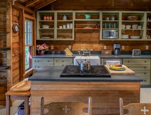 A wooden cabin interior with a central island, wooden cabinets, and a window.