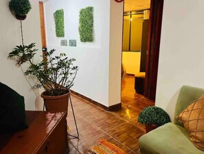Cozy space with a potted plant, plush chair, and green wall art, perfect for relaxation.