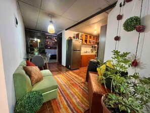 Cozy living space with a green sofa, dining table, and kitchen area.