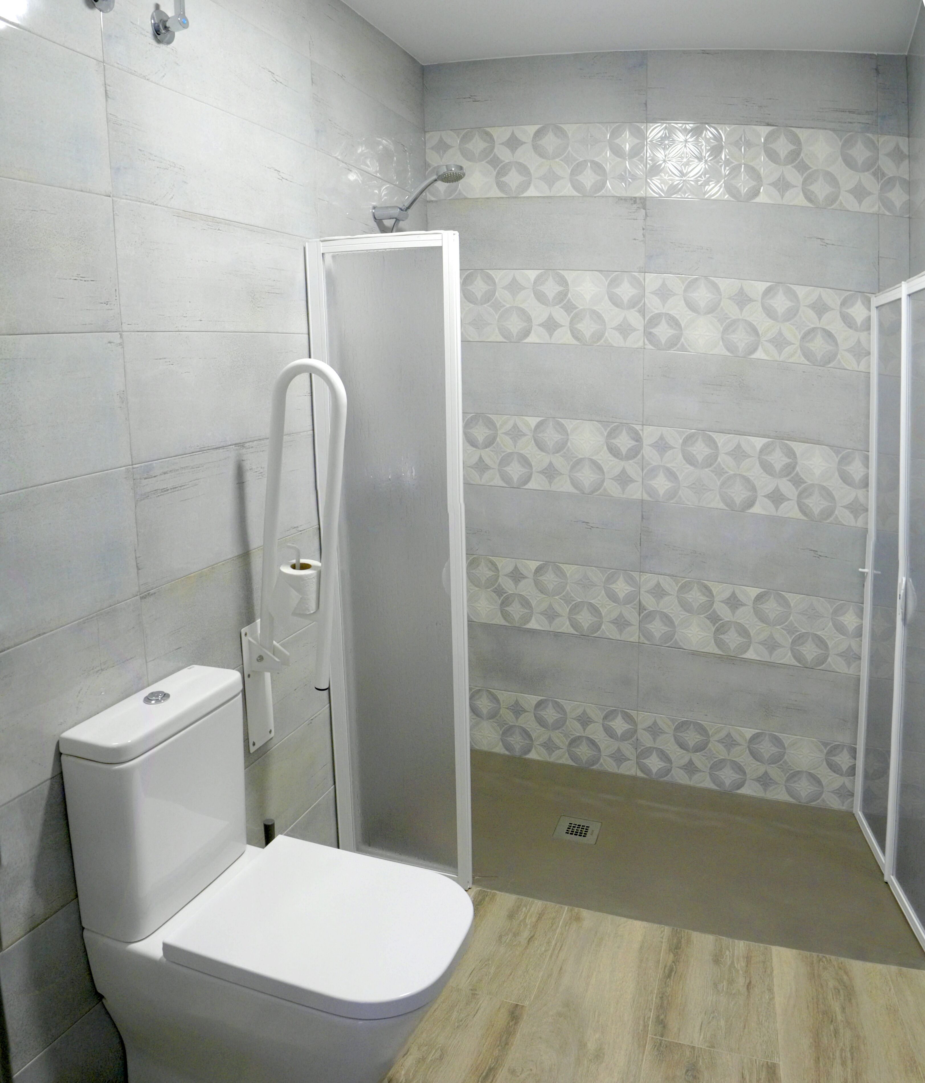 Une salle de bain comprenant des toilettes, un espace douche et des carreaux décoratifs sur les murs.