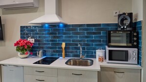 A modern kitchen with a stainless steel sink, a black induction cooktop, a white microwave, and a coffee maker. - CASAS RURALES MORADA DEL CERRO (Alcala del Jucar)