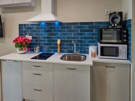 A modern kitchen with a stainless steel sink, a black induction cooktop, a white microwave, and a coffee maker.