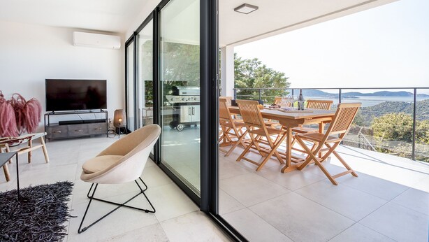 A modern living room with a TV, sofa, and dining area with a view of the outdoors. - Spacious villa w/ exceptional sea-view, pool & petanque ground _ 5 mn from beach (Lumio)