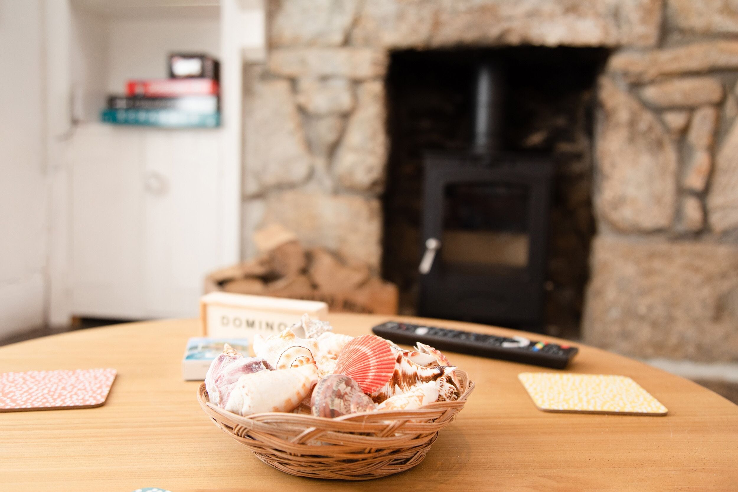 Una cesta de caracoles marinos sobre una mesa de madera, con una chimenea al fondo.