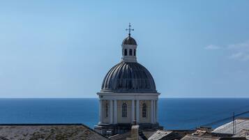 Une vue sur la côte, avec un imposant bâtiment blanc doté d’un dôme et d’une girouette, qui surplombe la mer.