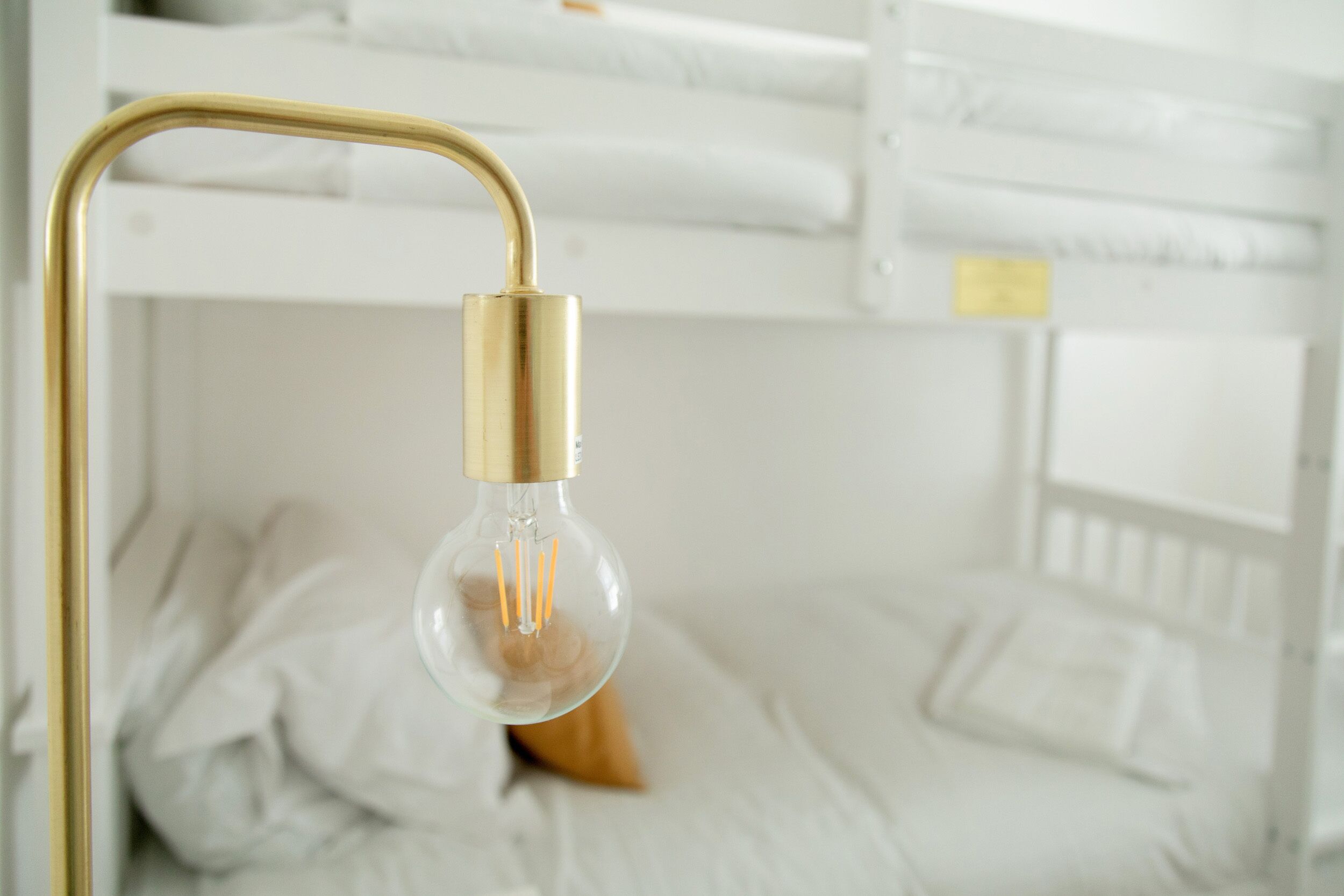 A bunk bed with a clear glass light fixture.
