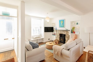 A living room with two sofas, a fireplace, a TV, and a bookshelf.