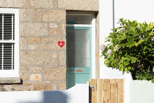 A stone building with a teal door and a heart-shaped number 11 sign.