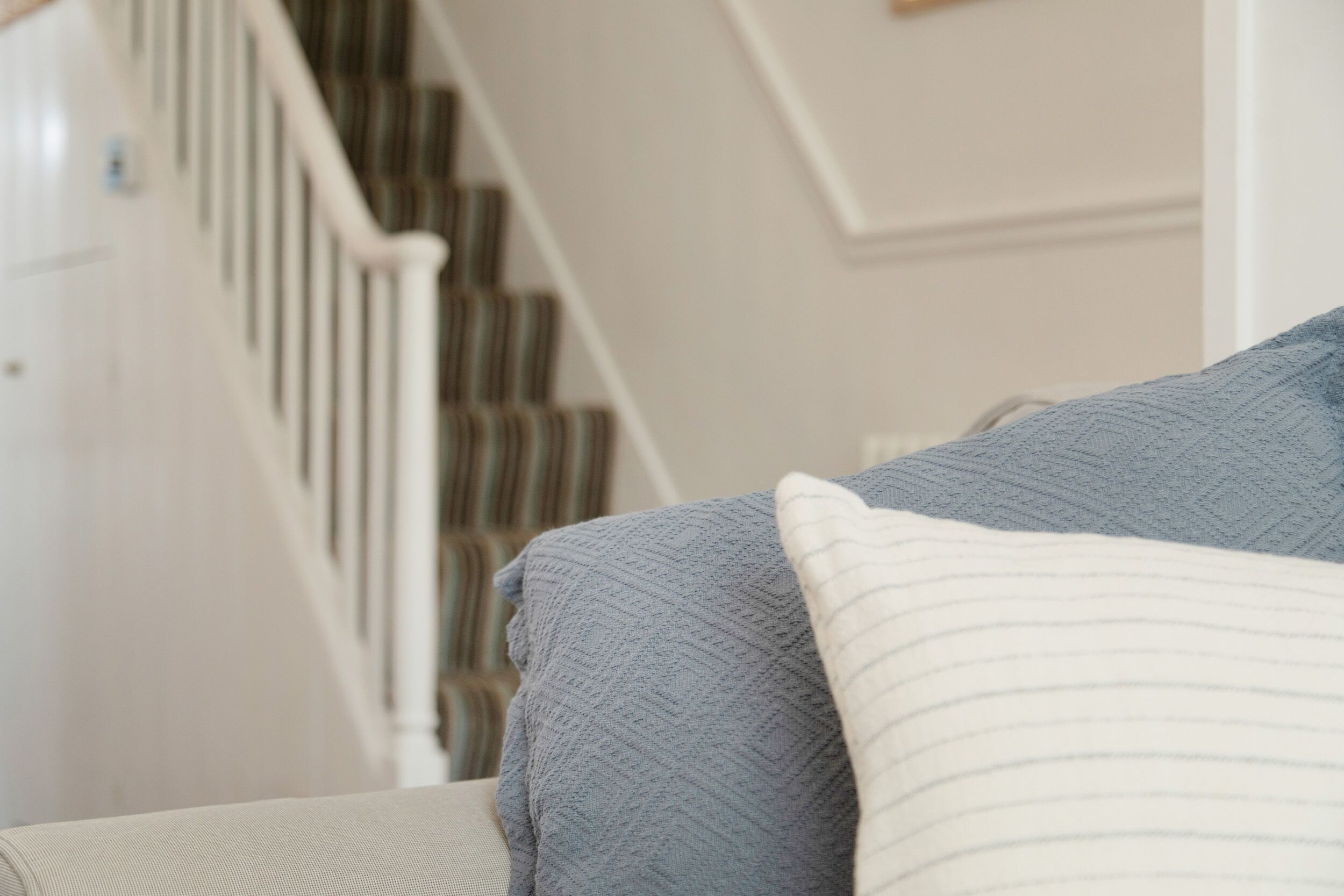 A staircase with a white railing and striped carpet.
